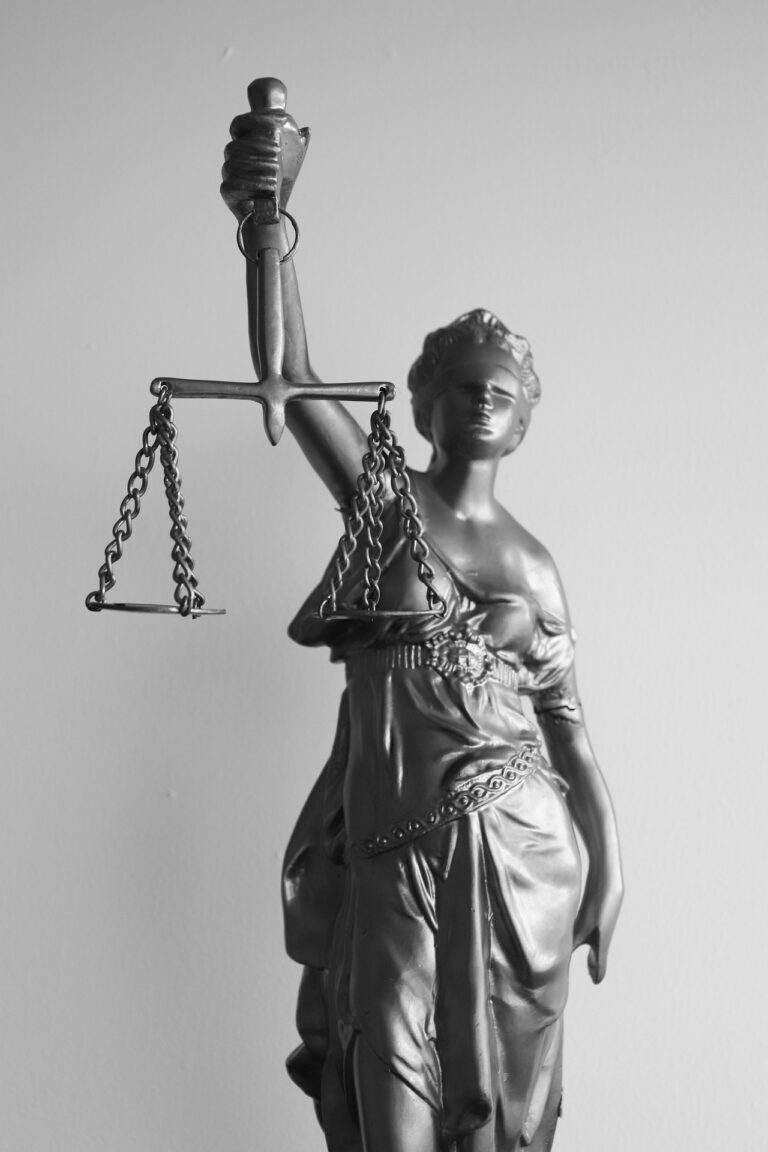 A statue of Lady Justice holding balanced scales in one raised hand.