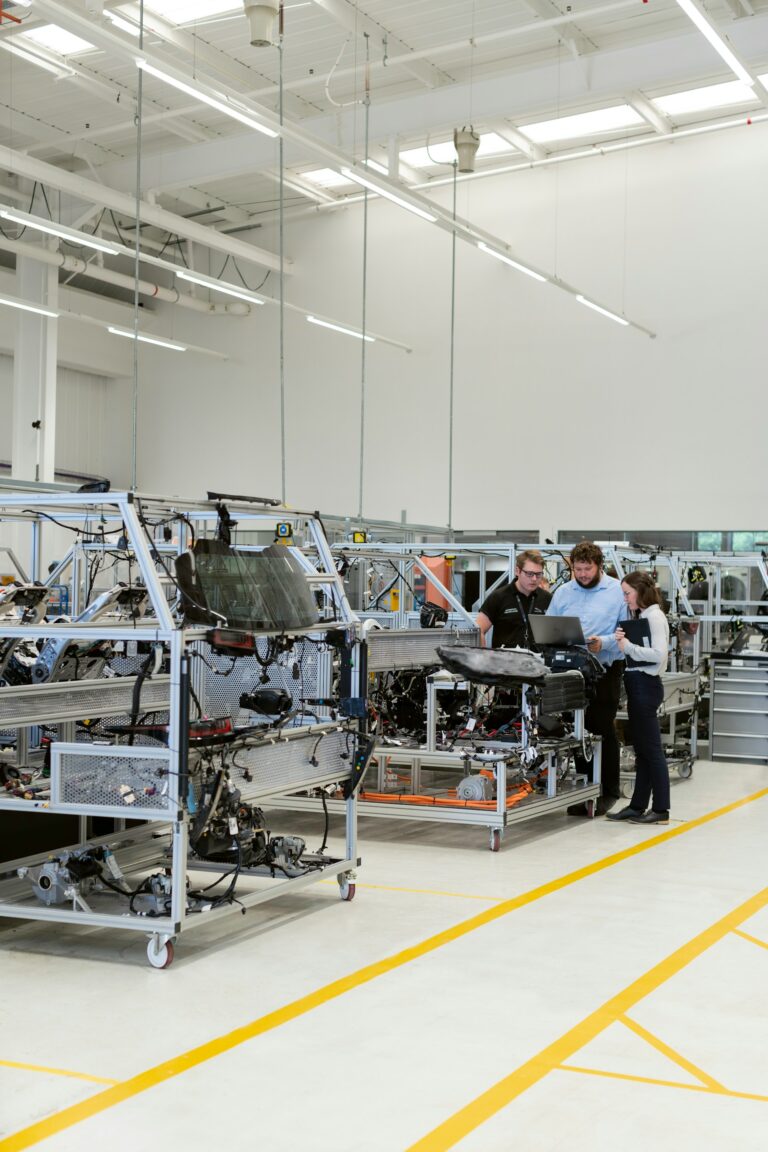 Three people discussing near machinery in a bright, modern industrial workshop.